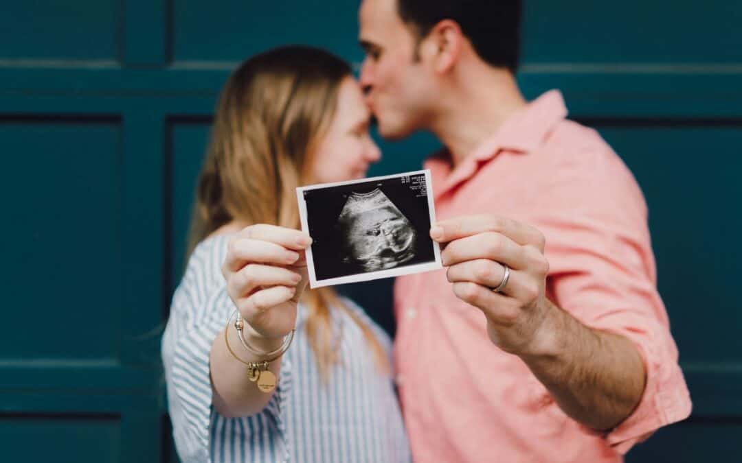 Man and woman holding up an ultrasound photo of their baby.